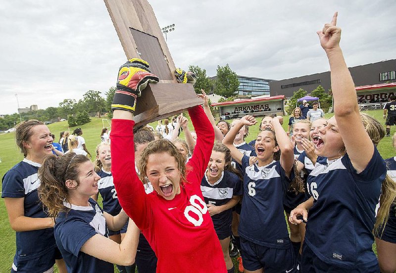 Little Rock Christian goal keeper Olivia Allen hoists the trophy with her teammates following the Warriors’ 2-1 victory in the Class 5A girls soccer final Friday.