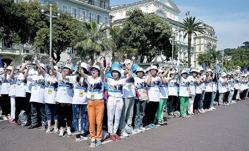 Employees of the Tiens Group — a Chinese company that sells medical products, including via direct marketing — cheer as they attend a parade organized by Chief Executive Officer Li Jinyuan on the Promenade des Anglais, Nice, in southeastern France earlier this month.
