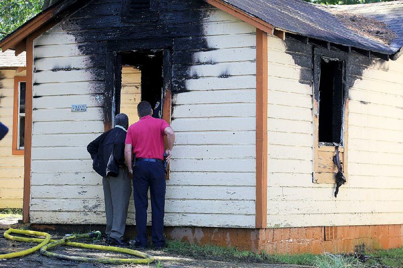 Little Rock police detectives Glenn King (left) and James Lesher inspect the scene of a house fire at 4721 W. 24th St. that left a man dead Friday morning. Delbert Griffith, 57, died at the scene, police said.