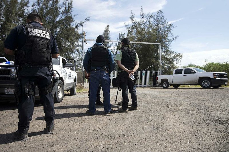 Armed men stand guard at the entrance of Rancho del Sol near Vista Hermosa, Mexico, on Friday. 