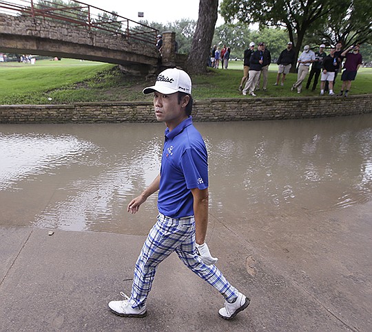 The Associated Press NO PLAY FOR NA: Kevin Na walks next to a rain-swollen drainage culvert adjacent to the 18th fairway where he lost his ball during the second round of the Colonial Friday in Fort Worth, Texas. Na made bogey on the hole but still finished with a 4-under 66, moving to 10 under for the tournament for a two-shot lead.