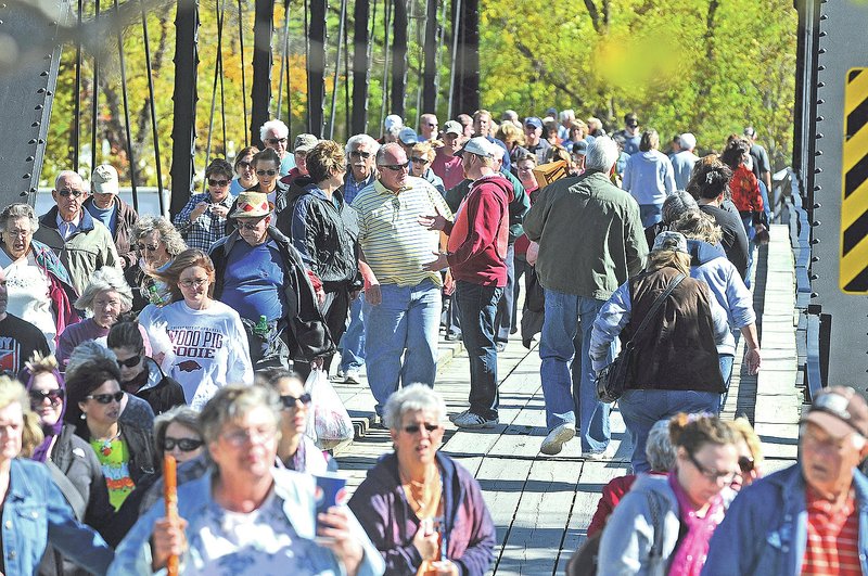 Pedestrians cross the War Eagle Bridge in 2012 to get to the War Eagle Mill Craft Show and the War Eagle Fair. Benton County officials are seeking an engineer to develop a plan to renovate the 1907 bridge.