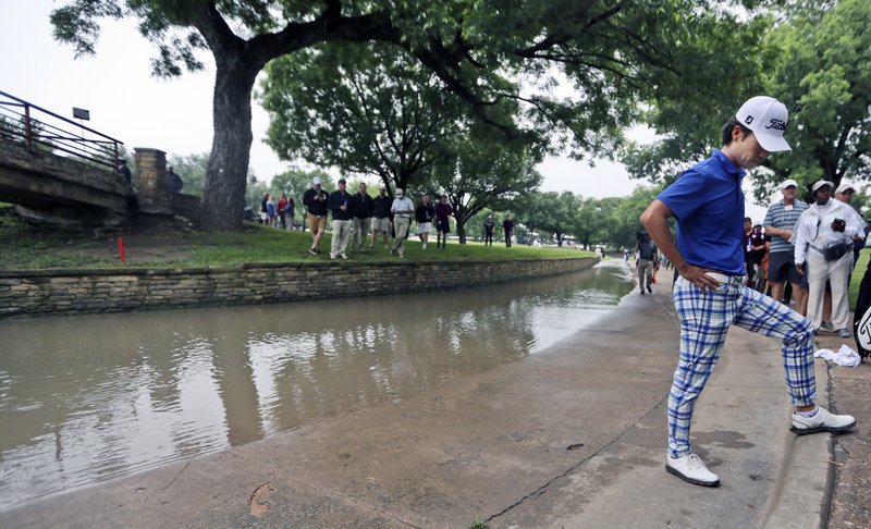 Kevin Na looks at the spot his ball landed before bouncing into a rain-swollen drainage culvert adjacent to the 18th fairway where he lost his ball during the second round of the Colonial golf tournament, Friday, May 22, 2015, in Fort Worth, Texas. Na recovered for par on the hole and is the leader at 10-under.