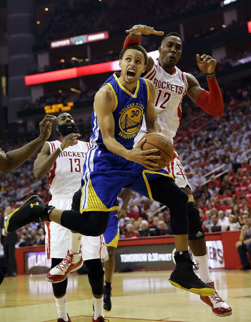 Golden State guard Stephen Curry (30) looks toward the basket Saturday before being fouled by Houston center Dwight Howard (12) during the first half in Game 3 of the NBA Western Conference fi nal. Curry had 40 points and seven assists in the Warriors’ 115-80 victory.