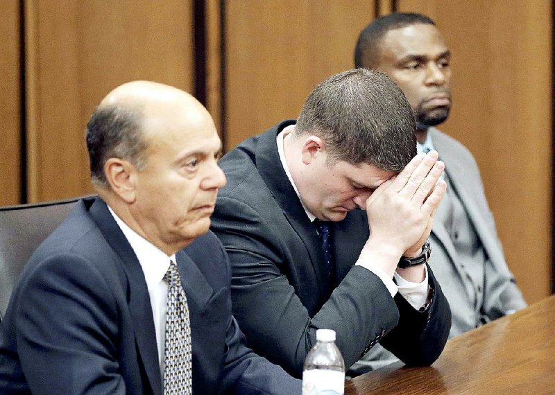 Patrolman Michael Brelo (center) sits with his defense team as the verdict is read Saturday in his trial over a fatal shooting in a car chase in 2012. 