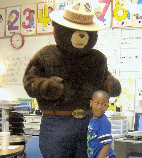 Submitted photo Langston Aerospace and Environmental Magnet School kindergartner Deshawn Smith hugs Smokey Bear during the school&#8217;s Earth Day celebration. Students learn how Smokey got his name and received a book about the famous bear.