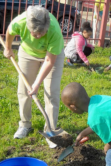 Submitted photo Garland County Master Gardeners Jan Hodges, left, and James Moore work with Kieron King, right, and other kindergarten students plant five trees on the grounds of Langston Aerospace and Environmental Magnet School for Earth Day on April 22. Students planted the new trees and learned how to care for them as part of the Earth Day celebration.