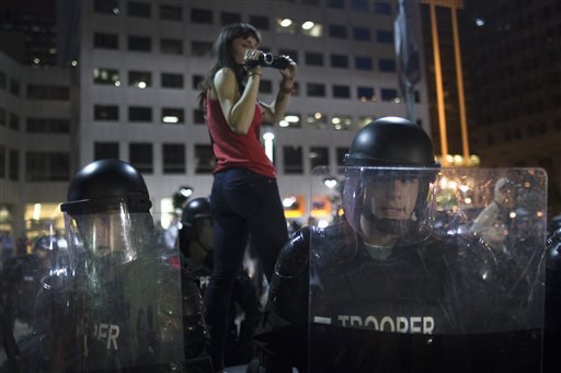 A protestor films riot police as they advance on a small march against the acquittal of Michael Brelo, a patrolman charged in the shooting deaths of two unarmed suspects, Saturday, May 23, 2015, in Cleveland. Brelo was acquitted Saturday in a case involving a 137-shot barrage of gunfire that helped prompt the U.S. Department of Justice determine the city police department had a history of using excessive force and violating civil rights. 