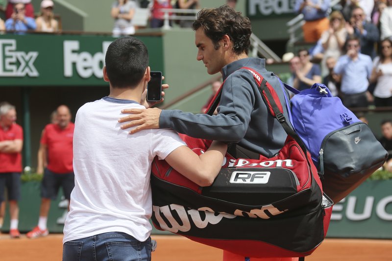 A boy who climbed down from the stands takes a selfie with Switzerland's Roger Federer in the first round match of the French Open tennis tournament against Colombia's Alejandro Falla at the Roland Garros stadium, in Paris, France, Sunday, May 24, 2015. 