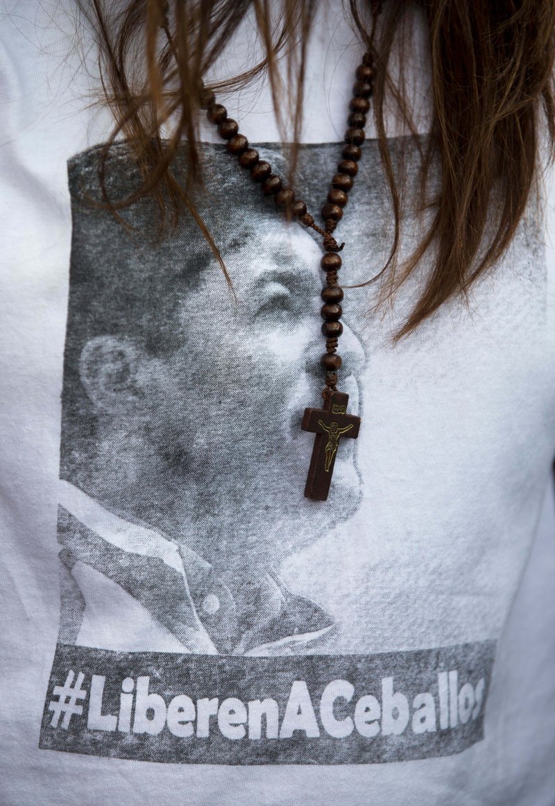  In this Friday, Jan. 23, 2015, file photo, San Cristobal's Mayor Patricia Gutierrez wears a rosary and a T-shirt with an image of her jailed husband Daniel Ceballos with a hashtag that reads in Spanish "Free Ceballos" at a protest in San Cristobal, Venezuela. 