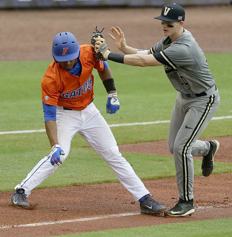 Florida baserunner Richie Martin (left) is chased down by Vanderbilt’s Will Toffey during the second inning of the weather-delayed SEC Tournament championship game Sunday. 