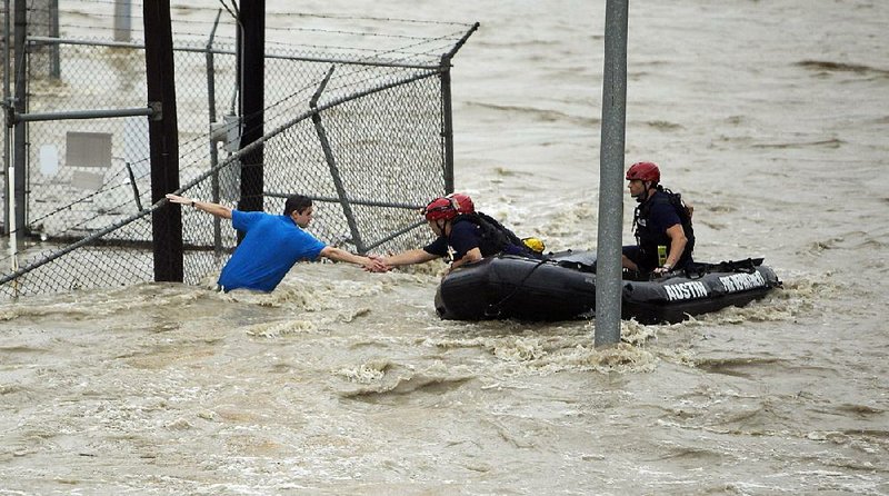 Rescue personnel grab the hand of a man stranded in rushing water Monday in Austin, Texas. Shoal Creek overflowed its banks and inundated parts of the city with rushing water.