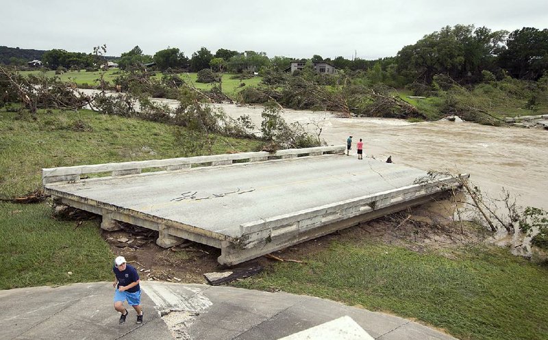 Dustin McClintock, 19, of Wimberley, Texas; Brandon Bankston, 18, of Blanco; and Hesston Krause, 22, of Smithson Valley on Sunday look at the Fischer Store Road bridge over the Blanco River near Wimberley that was destroyed by flooding.  