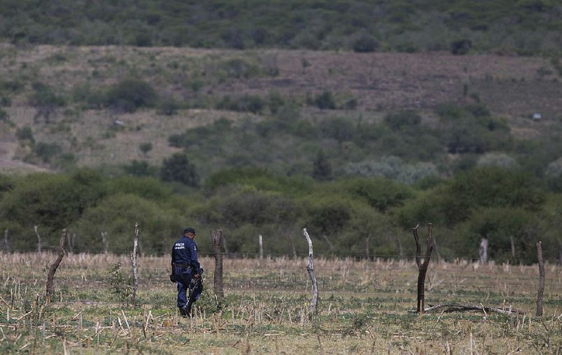 A police officer searches a field for evidence at the Rancho del Sol, a ranch that was the site of clashes between Mexican authorities and a drug cartel, in the municipality of Ecuandureo, Mexico on Saturday. 