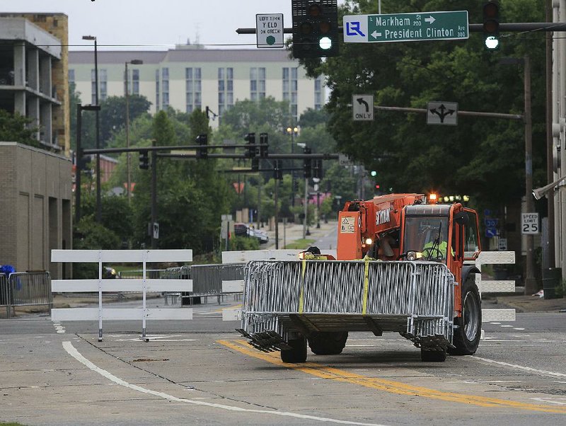 Workers pick up barriers in downtown Little Rock on Monday morning after Riverfest.