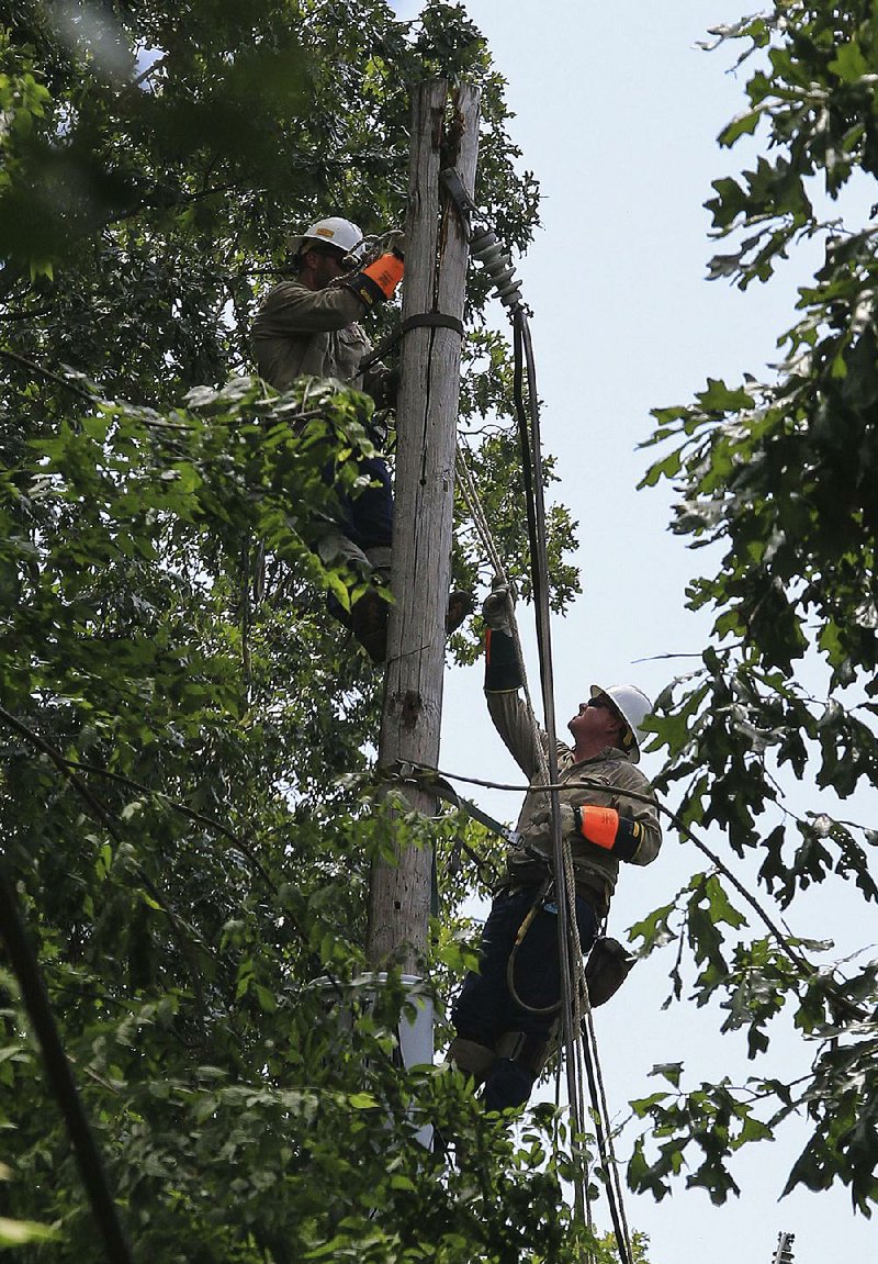 Utility workers work Monday afternoon to restore power in the Cammack Village area. Storms on Sunday night knocked out power to 20,590 Entergy customers throughout the state, a spokesman said.