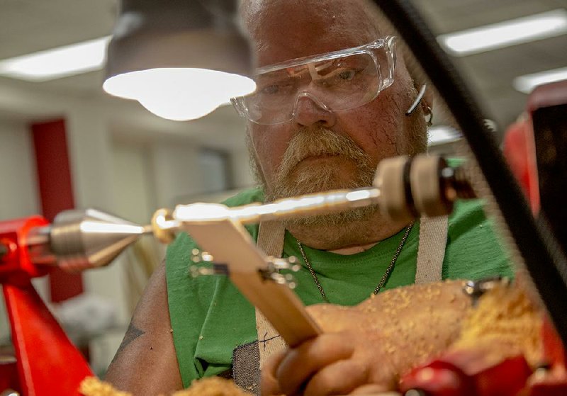 Jeffrey Bise uses a paper towel to apply wax to an olive-wood pen he was making on the lathe during a woodworking class last week at the Eugene Towbin Veterans Healthcare Center in North Little Rock. 
