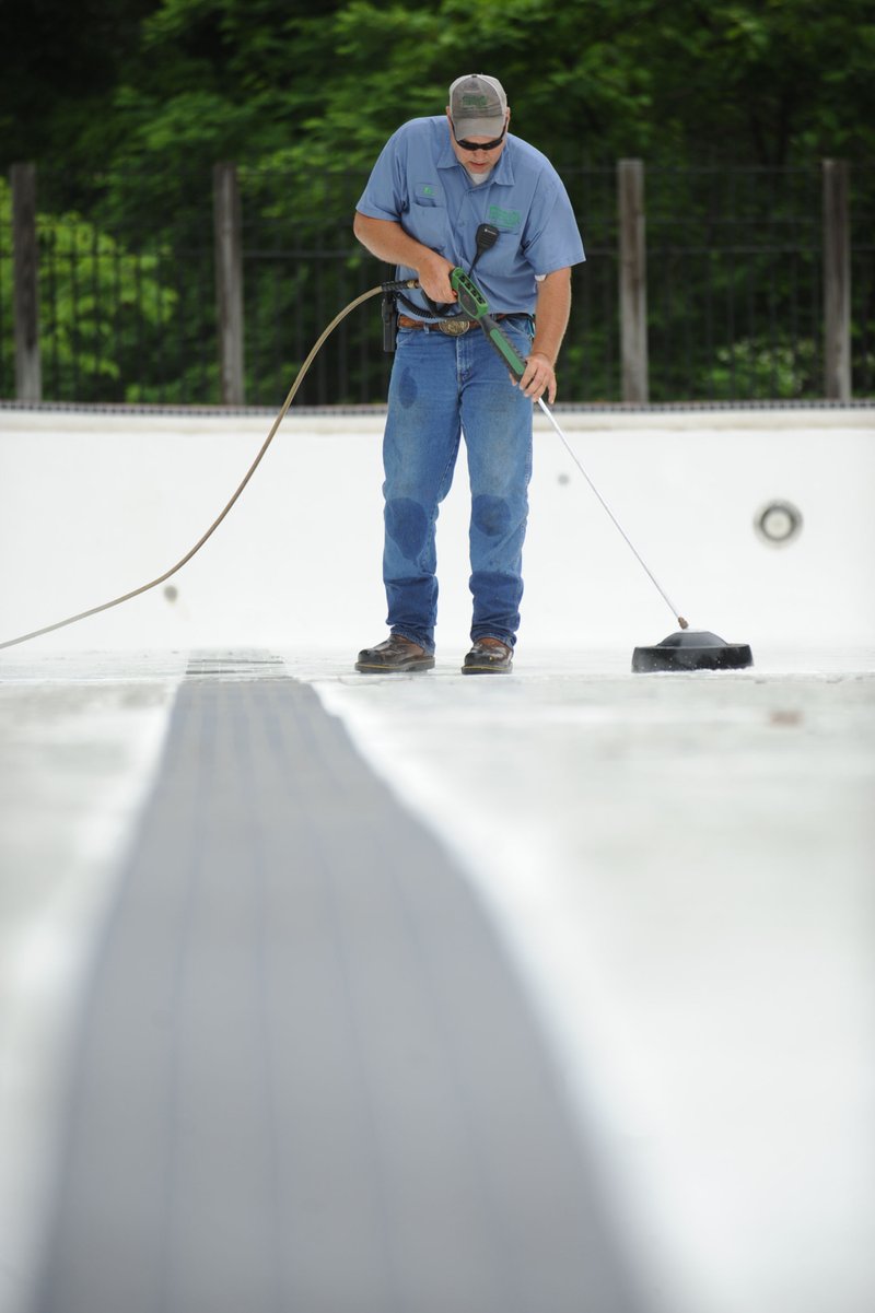 NWA Democrat-Gazette/ANDY SHUPE Eric Larson, longtime employee with the Fayetteville Parks and Recreation Department, uses a pressure washer Wednesday to clean the bottom of the pool in Wilson Park. The pool opens June 5 and will remain open through Aug. 16.