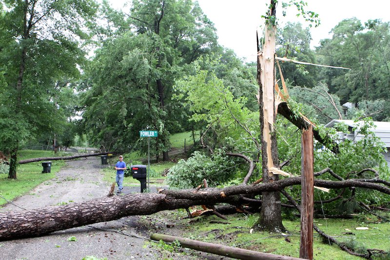 David Castle walks past his home on Cozy Acres Terrace near the intersection with Fowler Street in Mountain Pine on Tuesday. A storm that moved through the Garland County area Monday evening damaged numerous homes in the area. Photography by Richard Rasmussen of The Sentinel-Record.