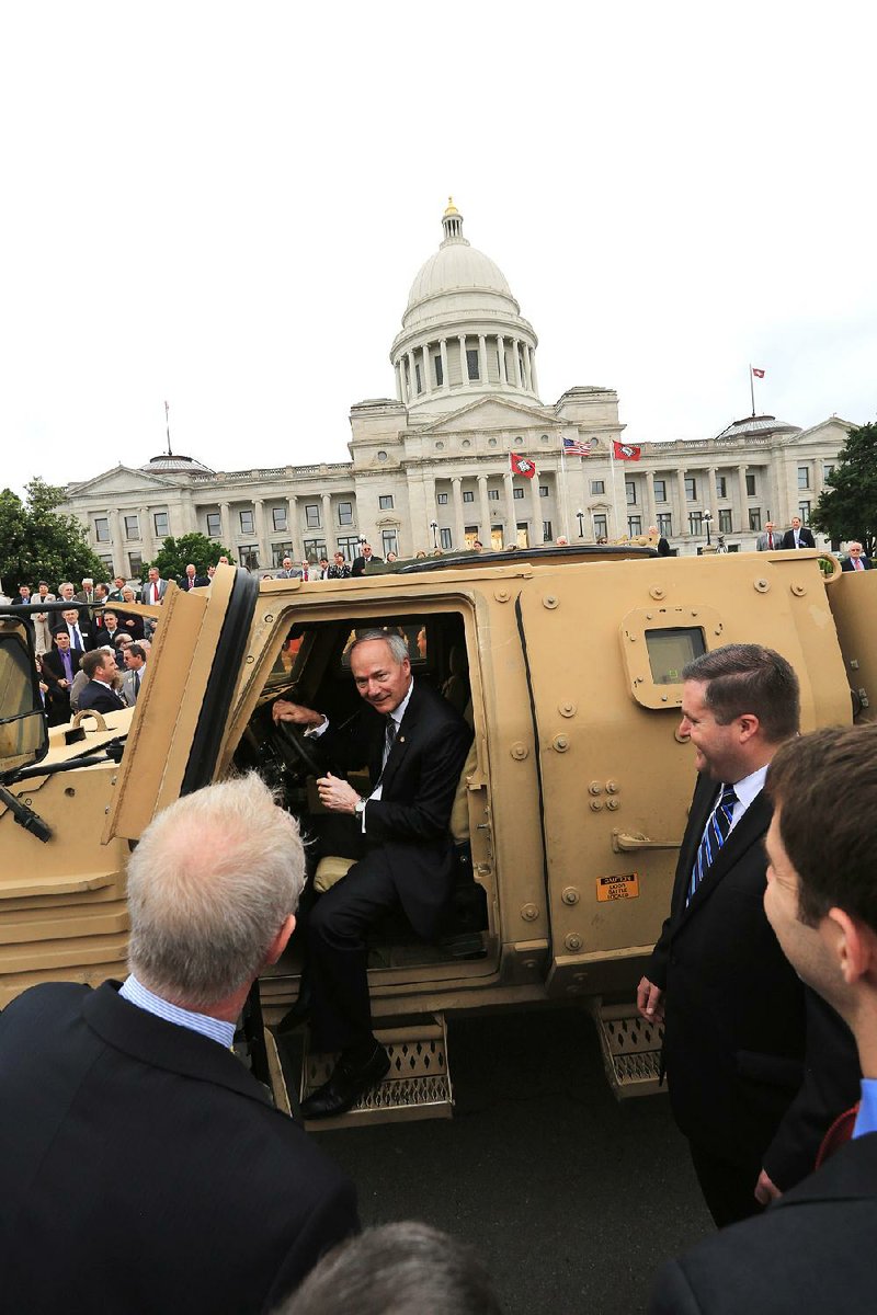 Gov. Asa Hutchinson tries out the driver’s seat of a Lockheed Martin joint light tactical vehicle that was parked Tuesday at the state Capitol before the start of a special session that includes measures to help get an assembly plant for the vehicle in Camden. With Hutchinson are (from left) Scott Green and Colin Sterling of Lockheed Martin and U.S. Sen. Tom Cotton. 