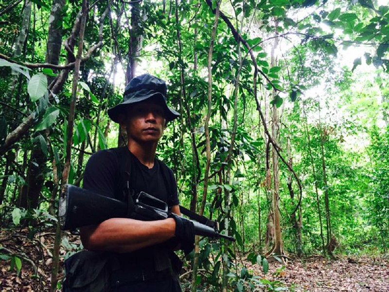 A Malaysian soldier leads the way into the jungle Tuesday for a visit to one of a cluster of abandoned camps used by human traffickers where more than 100 suspected graves and barbed-wire pens to cage people were found. 