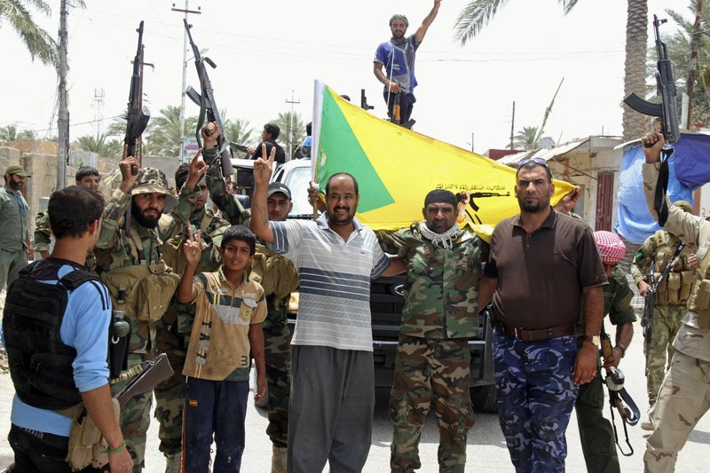 Local residents and Sunni tribal fighters welcome newly-arriving Iraqi Shiite Hezbollah Brigade militiamen,  brandishing their flag, who are joining the fight against Islamic State group militants in Khalidiya, 100 kilometers (60 miles) west of Baghdad, Iraq.