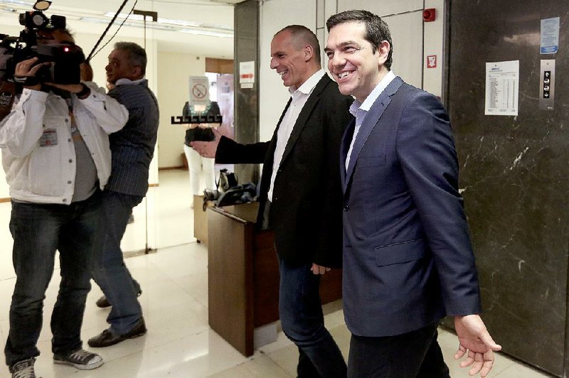 Greek Prime Minister Alexis Tsipras (right), is greeted Wednesday by Finance Minister Yanis Varoufakis at a meeting at the finance ministry in Athens. 