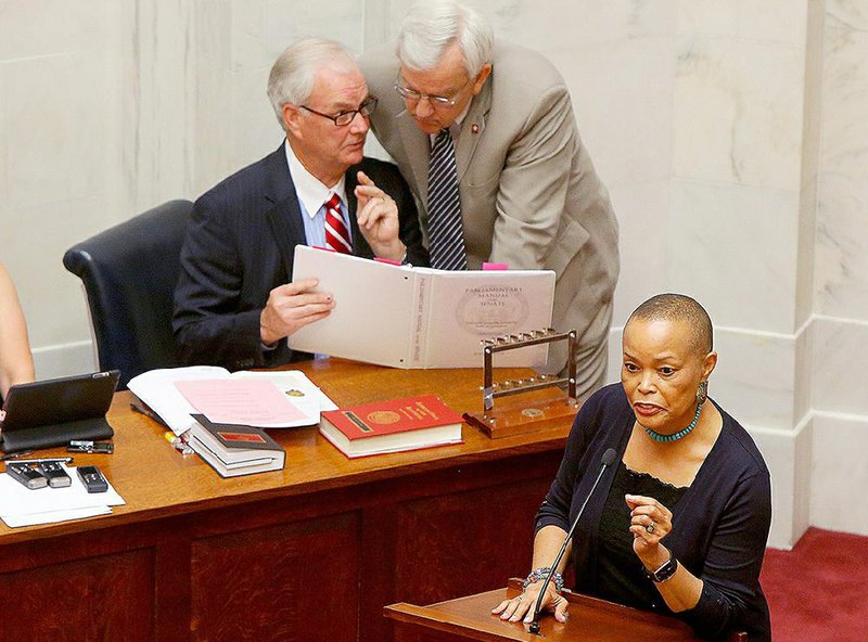 State Sen. Joyce Elliott, D-Little Rock, speaks Wednesday against a motion to extract a bill from a committee to move up the state’s primary elections after it had stalled. Behind her, Senate Chief Counsel Steve Cook (left) reviews Senate rules with Sen. Eddie Joe Williams, R-Cabot. Bills changing the date to March 1 finally moved through the Senate later in the evening. 