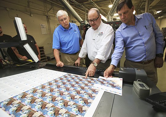 Arkansas Democrat-Gazette/Staton Breidenthal PHAROAH IN PRINT: Steve Arrison, CEO of Visit Hot Springs, left, looks over proofs of the American Pharoah trading card at Arkansas Graphics in Little Rock on Thursday with David Longinotti, director of racing at Oaklawn Racing and Gaming, and Greg Shira, vice president of production for CJRW. The cards will be distributed at Oaklawn on June 6 during the simulcast of the Belmont Stakes.