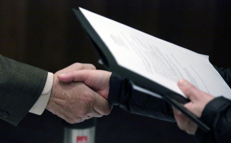 In this April 22, 2015 photo, Ralph Logan, general manager of Microtrain, left, shakes hands with a job seeker during a National Career Fairs job fair in Chicago. The U.S. Labor Department reports on the number of people who applied for unemployment benefits last week on Thursday, May 28, 2015.