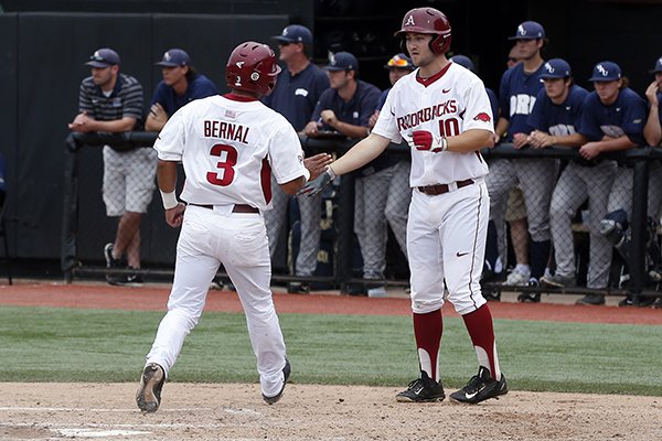 Arkansas's Michael Bernal (3) is congratulated by Joe Serrano (10) after Bernal scored off a single by Tucker Pennell against Oral Roberts in the third inning of a game at the Stillwater Regional of the NCAA college baseball tournament in Stillwater, Okla., Friday, May 29, 2015. (AP Photo/Sue Ogrocki)