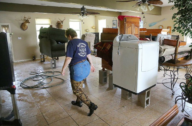 Wendy Emerson checks on pumps Friday in the living room of her home on Holiday Drive at Island Harbor Estates in Pine Bluff. Earlier in the week, she and her husband began putting their furniture on blocks and setting up pumps as the Arkansas River encroached.