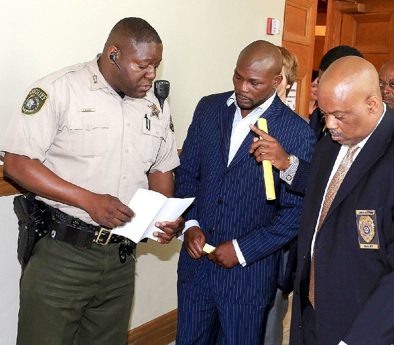 A Pulaski County sheriff’s deputy serves boxer Jermain Taylor with a second-degree battery warrant after a Friday court appearance as bailiff Lynn Berry escorts Taylor to a holding area at the county courthouse in Little Rock. 
