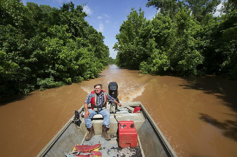 Bobby Older of Fulton navigates his boat up a private road normally used by trucks Sunday while checking his property along the west bank of the Red River. 