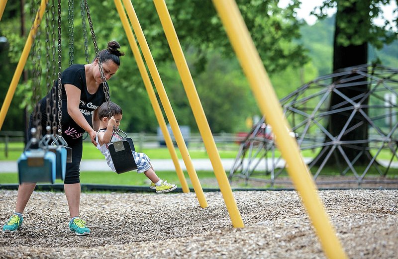 Carla Gonzalez of Rogers pushes her son Carlos Gonzalez, 2, on a swing set on Thursday at Lake Atalanta in Rogers.