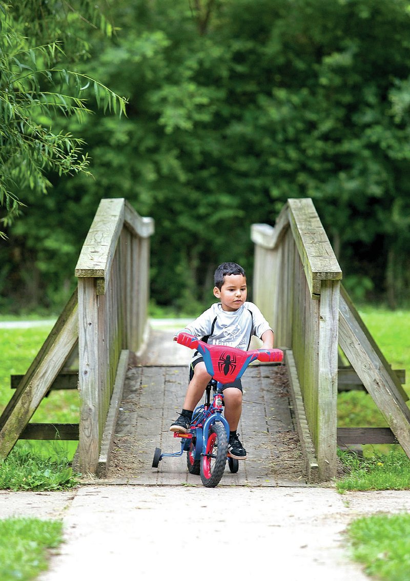 Ignacio Gonzalez, 4, of Rogers, rides his bicycle around the park Thursday at Lake Atalanta in Rogers.