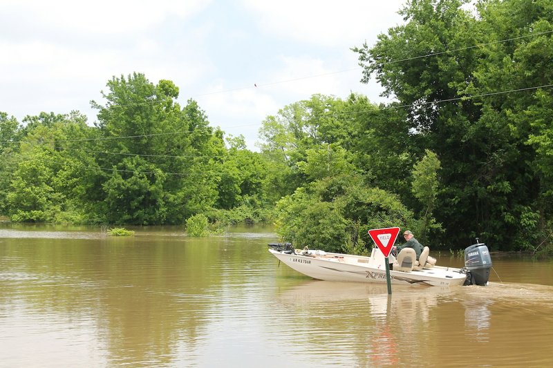 A man boats across a flooded area near the entrance of Island Harbor Estates neighborhood in Pine Bluff on Monday, June 1, 2015. 