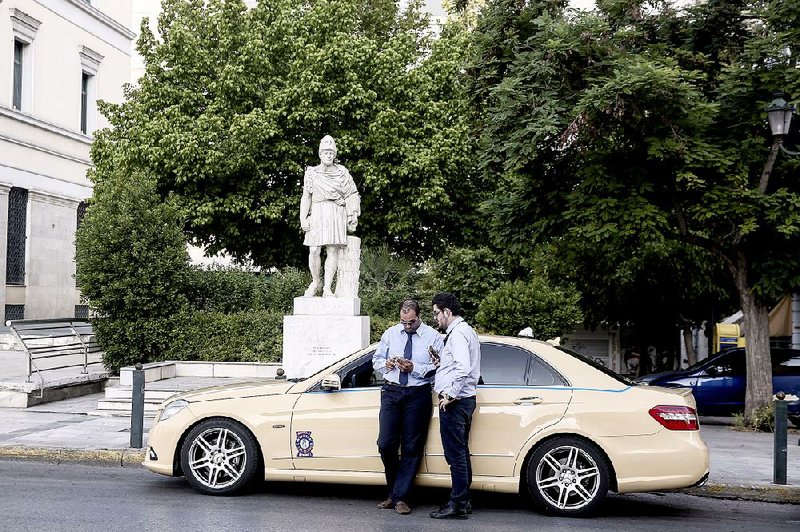 Taxi drivers look at a smartphone Sunday in Athens, Greece. The Greek government failed to meet its promise to reach an agreement with lenders over the weekend. 