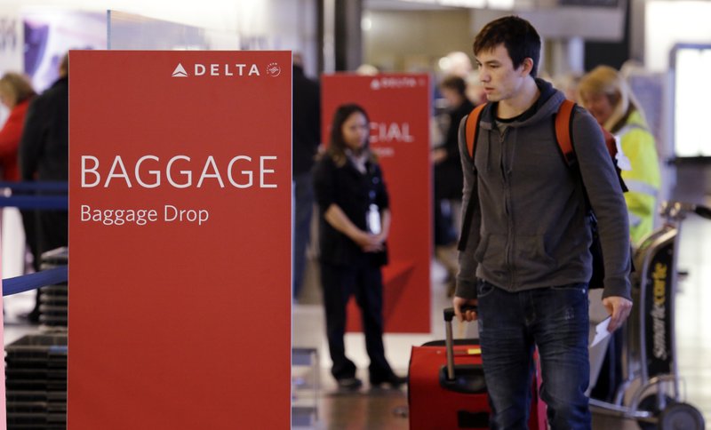 In this photo taken Tuesday, March 24, 2015, travelers walk toward the baggage drop area for Delta airlines at Seattle-Tacoma International Airport in SeaTac, Wash. This summer travel season, Delta plans to preload carry-on bags above passengers seats on some flights.