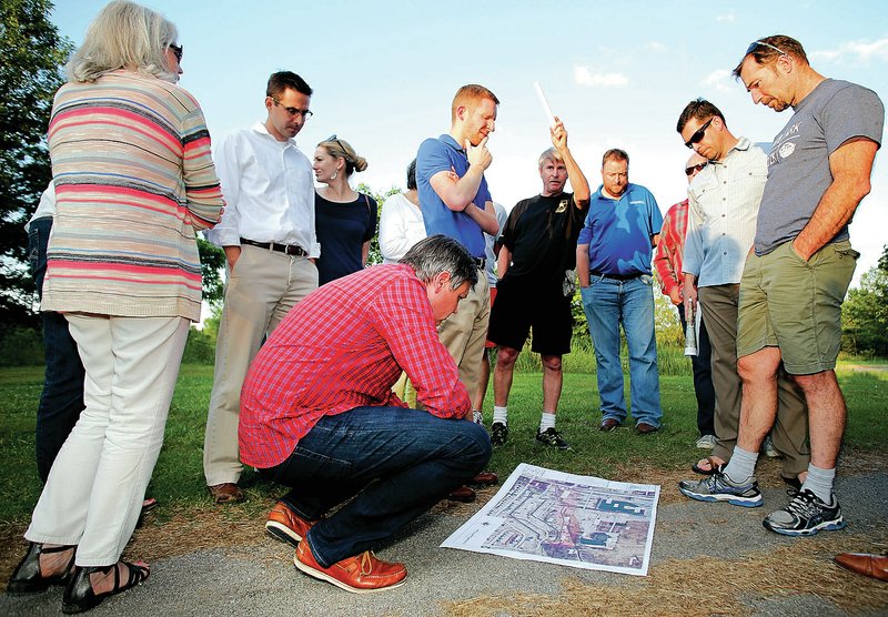 John Scott Bull kneels Monday to take a closer look at a map of the Razorback Park Golf Course and surrounding neighborhoods with members of the city Parks and Recreation Advisory Board at the golf course in Fayetteville. A company registered to Jim Lindsey has submitted plans for a residential development on the golf course. For photo galleries, go to nwadg.com/photos.