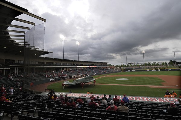 Workers pull a tarp over the field during a rain delay Sunday, May 10, 2015, at Baum Stadium in Fayetteville. 