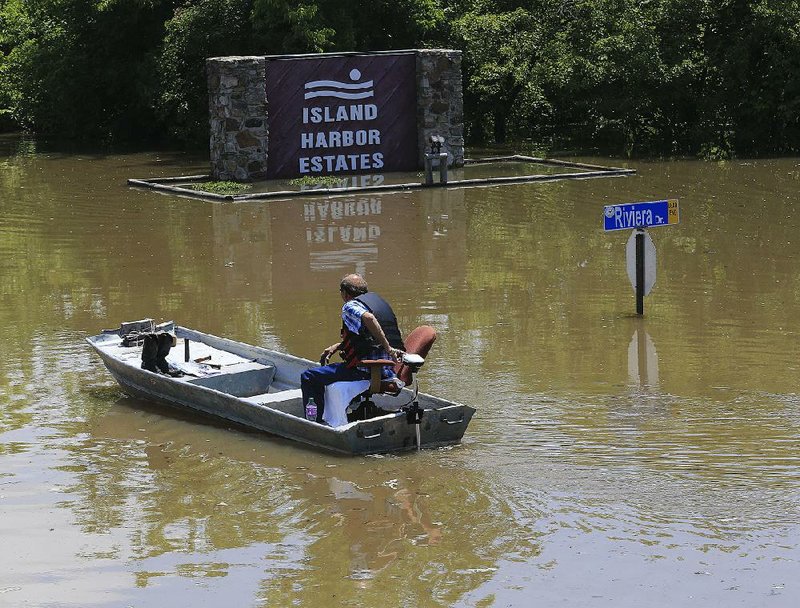 Jerry Trammell heads to his house on Riviera Drive in the Island Harbor Estates neighborhood of Pine Bluff on Tuesday. Trammell said the water had not reached the inside of his home.