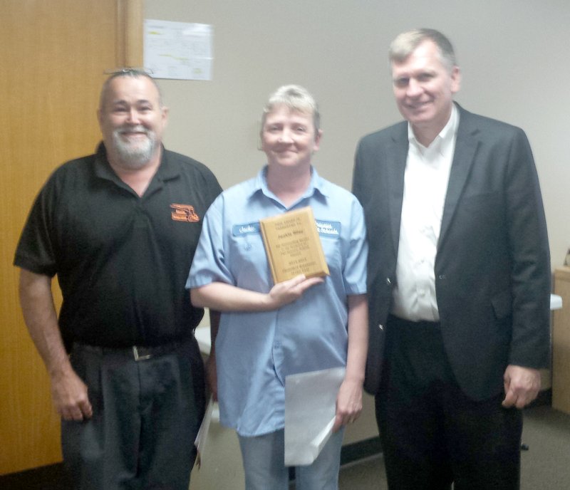 Photo by Mandy Barrett Jackie Riley displays the plaque she was awarded at the May school board meeting honoring her as &#8220;Classified Employee of the Year&#8221; for Gravette schools. Jackie has worked for the school system five years and is now head of the night custodial crew. Richard Carver, left, maintenance supervisor, read a letter from Glenn Duffy Elementary principal Zane Vanderpool praising Riley for her work and commenting that she &#8220;prepares students for achievement by maintaining a clean learning environment.&#8221; School board president Jay Oliphant presented the award.