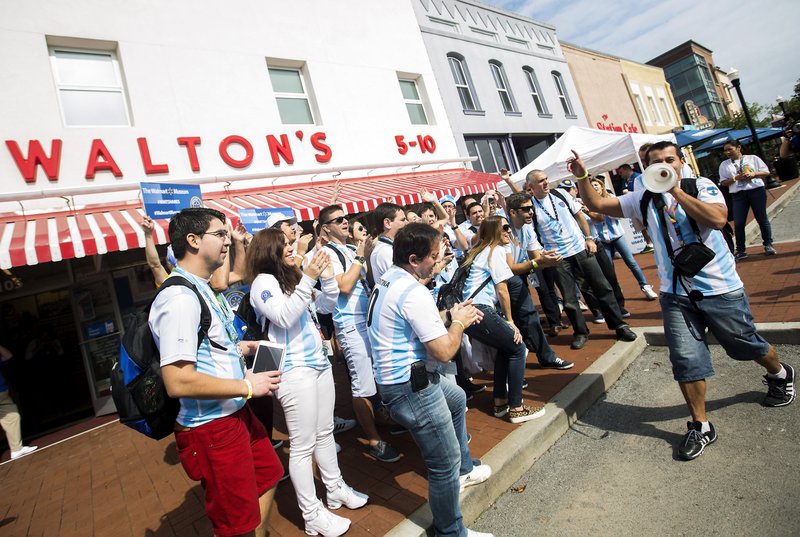 Walmart employees from Argentina cheer Tuesday outside the entrance of the Walmart museum in downtown Bentonville. The group is in Northwest Arkansas for the annual shareholders meeting. See special section inside today’s edition. For photo galleries, go to nwadg.com/photos.