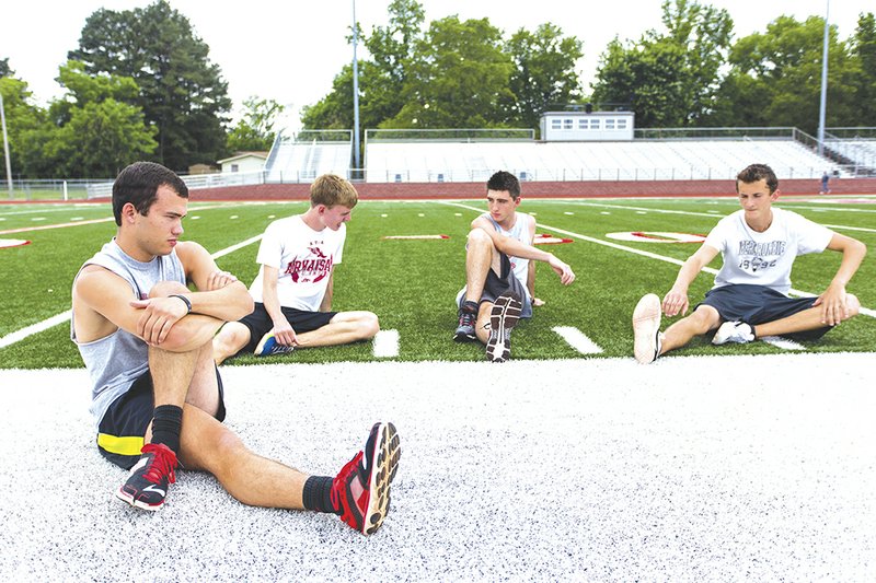 Malachi Cannon, from left, Jon Ogle, Steven Childress and Christian Dawkins stretch on the Heber Springs High School football field before a track practice. The boys are part of the Panthers track team that won the unofficial Arkansas boys high school triple crown — indoor track and field, outdoor track and field, and cross country — this year, giving the school a trio of such victories.