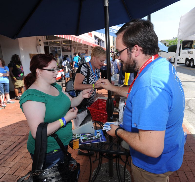 NWA Democrat-Gazette/ANDY SHUPE Rebecca Yzaguirre (left), a Sam&#8217;s Club employee from Indianapolis, exchanges pins with Nicholas Graves, archivist for the Walmart Museum, on Wednesday on the Bentonville square. Yzaguirre and other employees are in the area for the annual shareholders meeting. For photo galleries, go to nwadg.com/photos.
