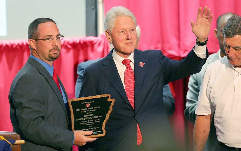 Former President Bill Clinton acknowledges applause as he is awarded a plaque Thursday evening inducting him into the Arkansas Boys State Hall of Fame from Rusty Bush, coordinator of the Arkansas Boys State Commission, at the University of Central Arkansas campus in Conway. 