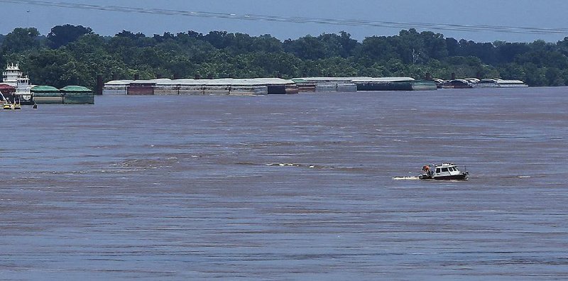 A boat navigates the swollen Arkansas River over a natural gas pipeline that ruptured Sunday morning about a mile east of the Interstate 30 bridge. Pipeline owner Spectra Energy Corp. has sent a crew to survey the line.