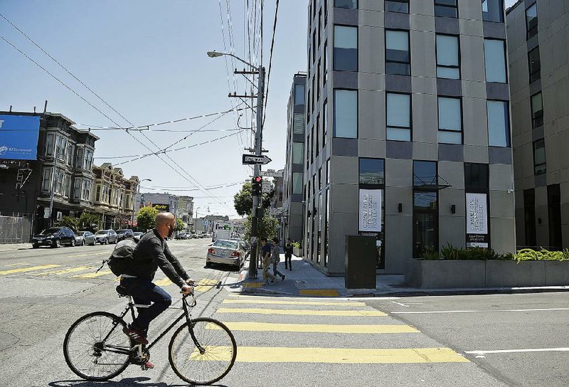 A man rides his bike past a new 40-unit Mission District condominium development earlier this month in San Francisco. 