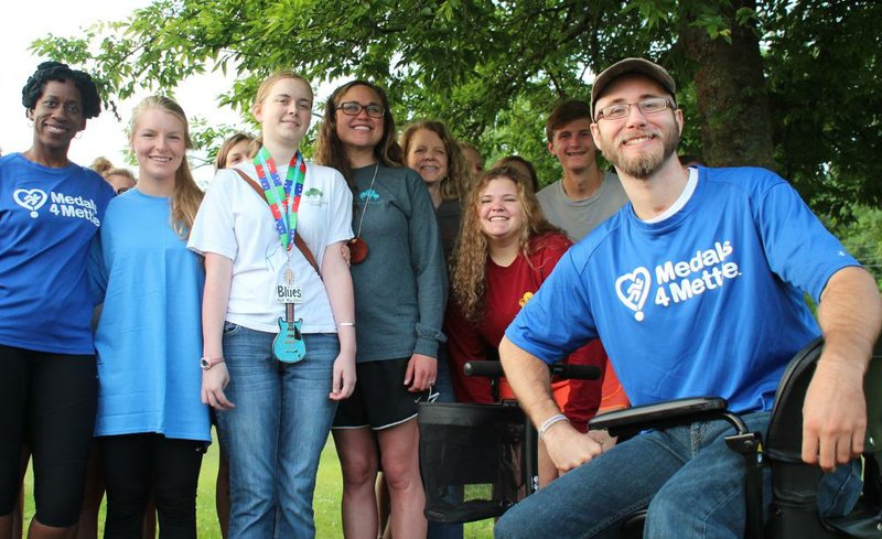 Wearing her new medal, Katie Tyree is surrounded by well wishers just after sunrise Wednesday in Murray Park, including Brenda Ngozi Stallings (far left), Ali Miller (at Tyree’s right), her mother, Carol Tyree (behind Miller), and (seated) the 2014 Medals4Mettle honoree, Cole Parker of Conway.
